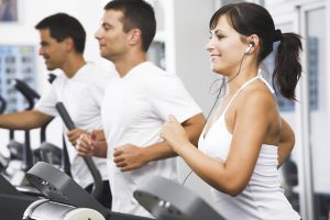 Young adults using running machine at the fitness club